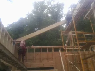 Carpenter raising a rafter beam on a new second story frame in Sutter